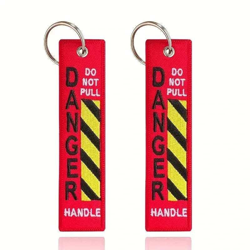 Schlüsselanhänger Danger für Gleitschirmpiloten, hochwertig gewebt, als Gurtzeug- oder Schlüsselanhänger nutzbar, abgebildet in Nahaufnahme.