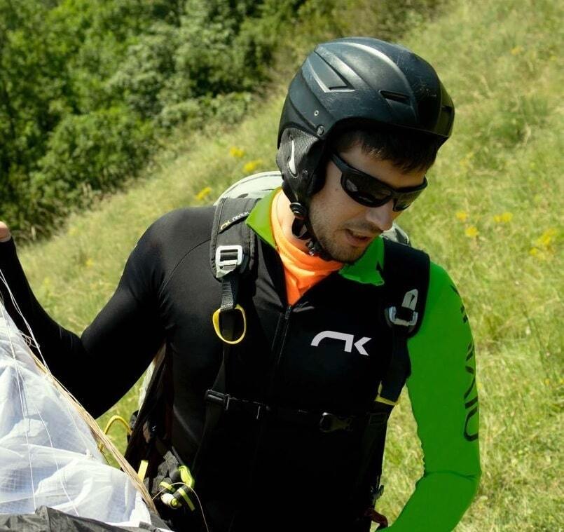 Mann mit Helm und Sonnenbrille trägt Niviuk Paragliding Speedarms R-Series, ideal für Piloten, schützt vor Abrieb und bietet aerodynamischen Komfort.