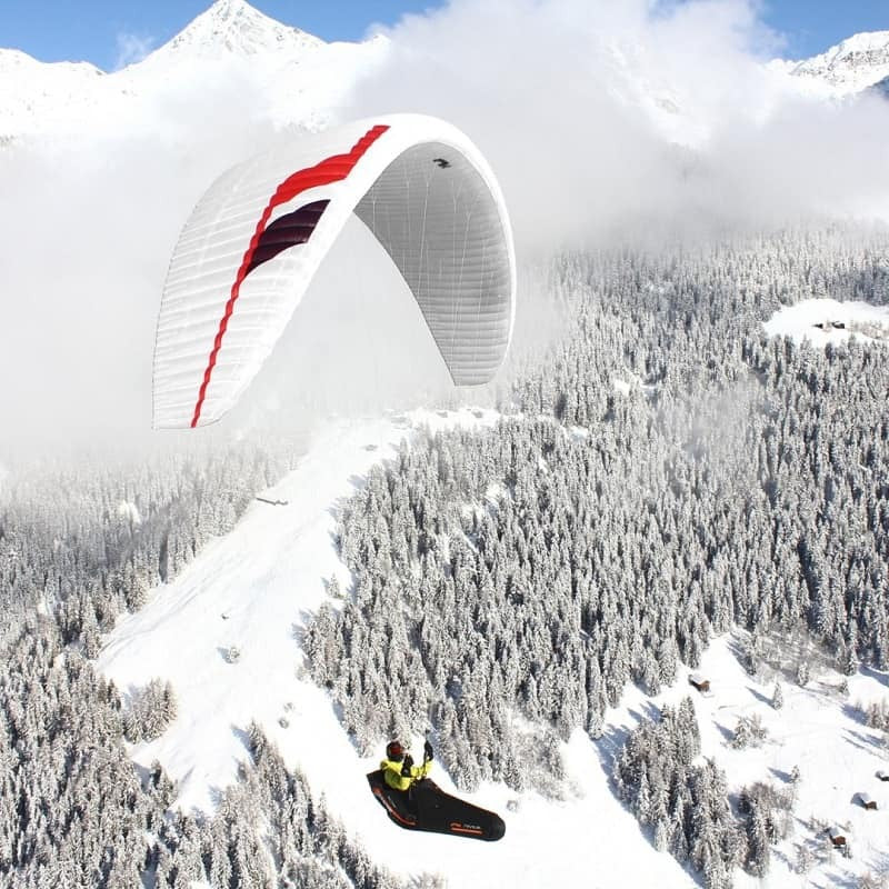 Niviuk Klimber 3P: Ein Pilot fliegt mit einem ultraleichten Paraglider über verschneite Berge, ideal für erfahrene Bergliebhaber und Hike-&amp;-Fly-Abenteuer.