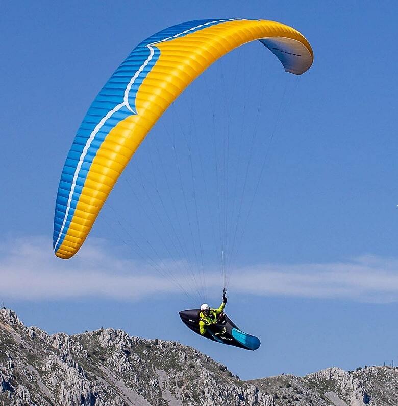 Ozone Delta 4 (EN-C) Gleitschirm mit rotem Schirm und Pilot in Aktion, ideal für fortgeschrittene Flieger.