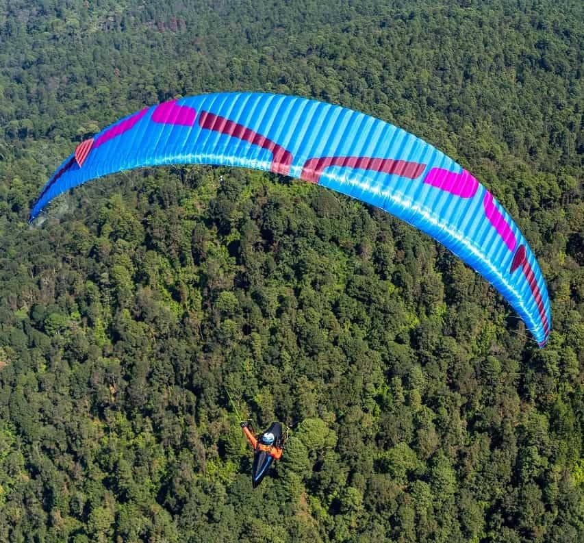 Ozone Photon (EN-C) Gleitschirm, gelber Schirm, Person beim Paragliding in der Luft, ideal für erfahrene Sportklasse-Piloten.