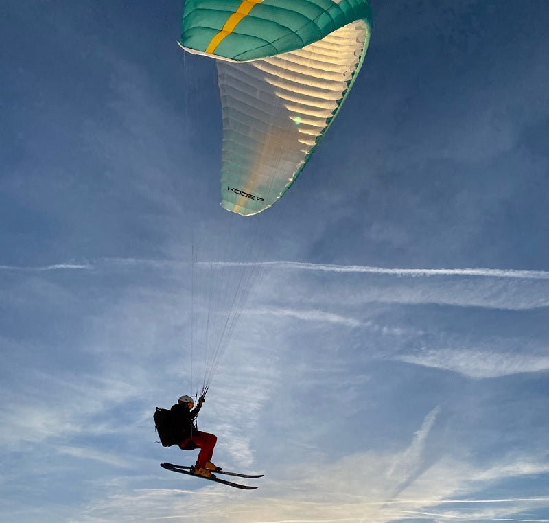 Person gleitet mit Niviuk Kode P Gleitschirm durch die Luft, demonstriert geringes Gewicht und hohe Manövrierfähigkeit, ideal für erfahrene Piloten bei Hike &amp; Fly Abenteuern.