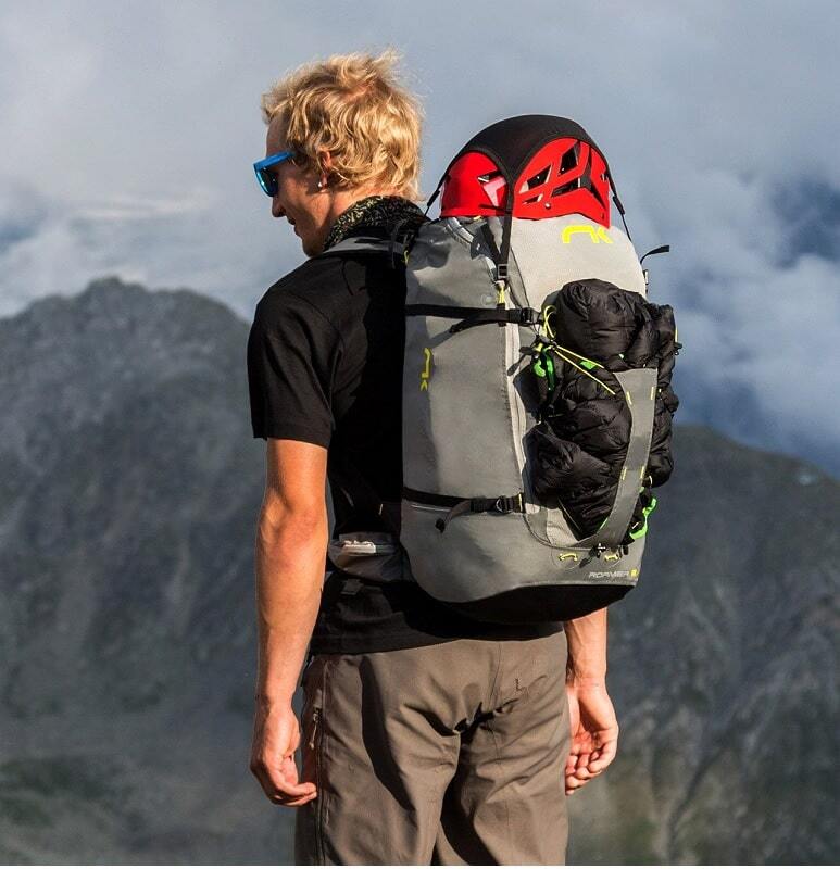 Mann mit Niviuk Roamer 2 Hike&amp;Fly Gurtzeug und Schlafsack, bereit für Bergabenteuer, zeigt Komfort und Effizienz des innovativen Tragesystems.