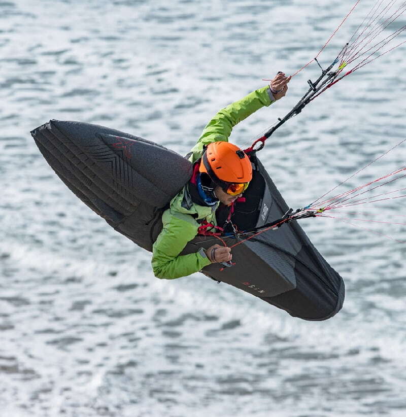 Person gleitet mit dem GIN Genie X-Lite XC-Gurtzeug beim Paragliding. Ideal für XC und Hike &amp; Fly, bietet Komfort und Stabilität.