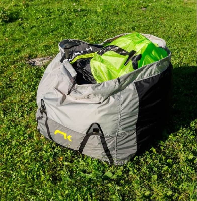 Niviuk Koli Pro Tandem Schnellpacksack auf Gras liegend, ideal für schnelles, sicheres Packen von Flugausrüstung, mit elastischem Kordelzug und verstellbaren Trageriemen.