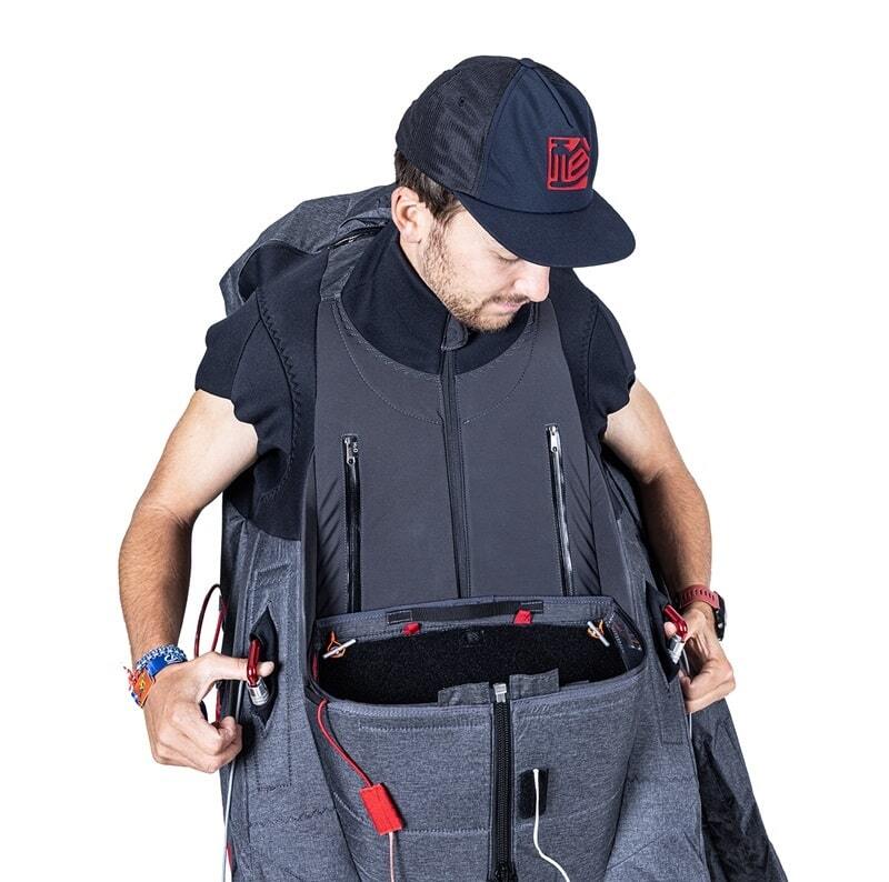 GIN Genie Race 5 - Competition Gurtzeug, getragen von einem Mann, der seinen Rucksack betrachtet; bekannt für Leistung und Ergonomie im Gleitschirmsport.