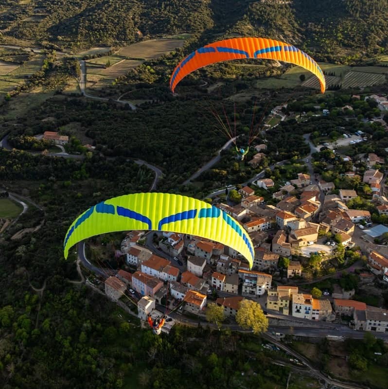 Ozone Buzz Z7 Gleitschirm beim Paragliding über einer Stadt, zeigt innovative Flügelform und verbesserte Stabilität, ideal für XC-Flüge mit hoher passiver Sicherheit.