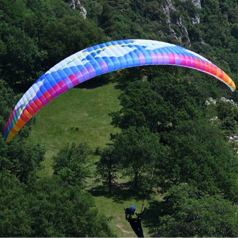 Person beim Paragleiten mit blau-lila BGD Base 2 Light Gleitschirm, einem leistungsstarken, leichten Schirm für Hike-and-Fly-Abenteuer.