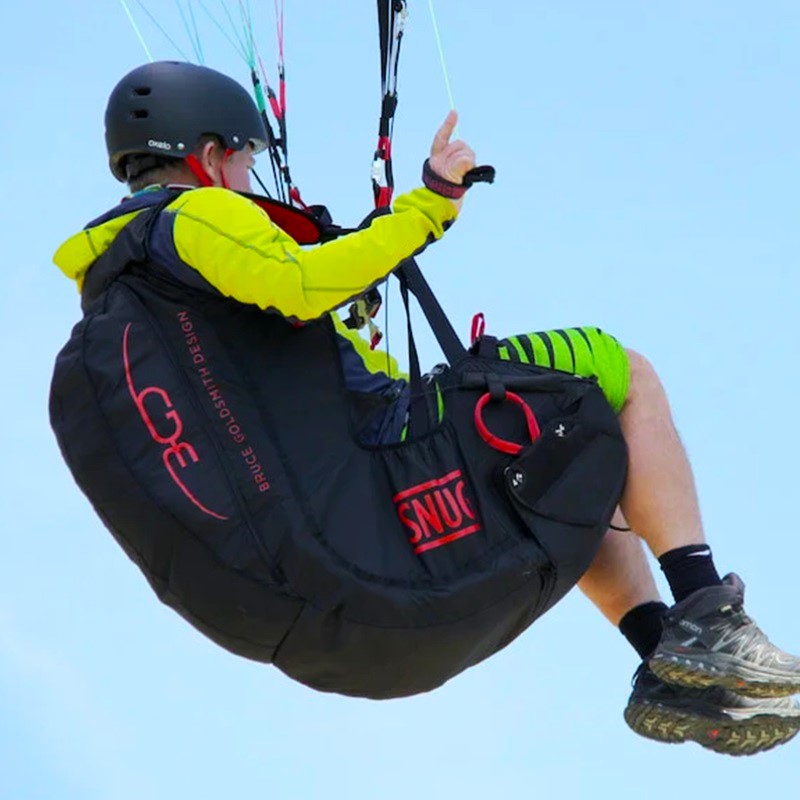 Person beim Paragleiten mit BGD Snug Sitzgurtzeug in der Luft, das für Komfort und Sicherheit während des Fluges entwickelt wurde.