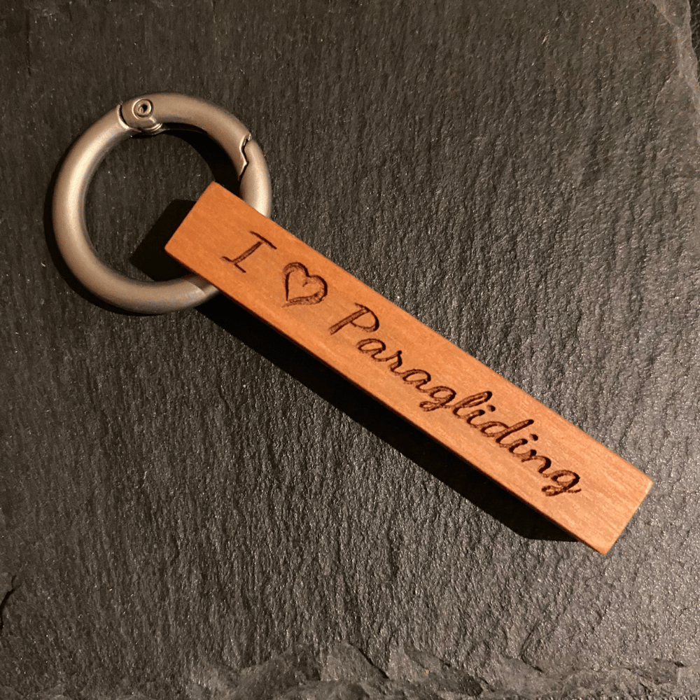 Echtholz Schlüsselanhänger I Love Paragliding aus Kirschholz mit Gravur und Gleitschirmmotiv, befestigt an einem matten Aluring.