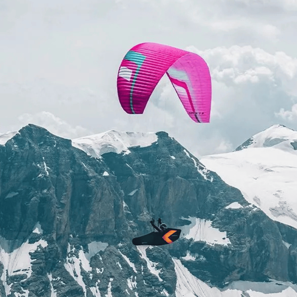 Paraglider Niviuk Artik 7 P (EN-C) fliegt über Berglandschaft, ideal für fortgeschrittene Hike &amp; Fly-Piloten, bekannt für Leichtigkeit und Stabilität.