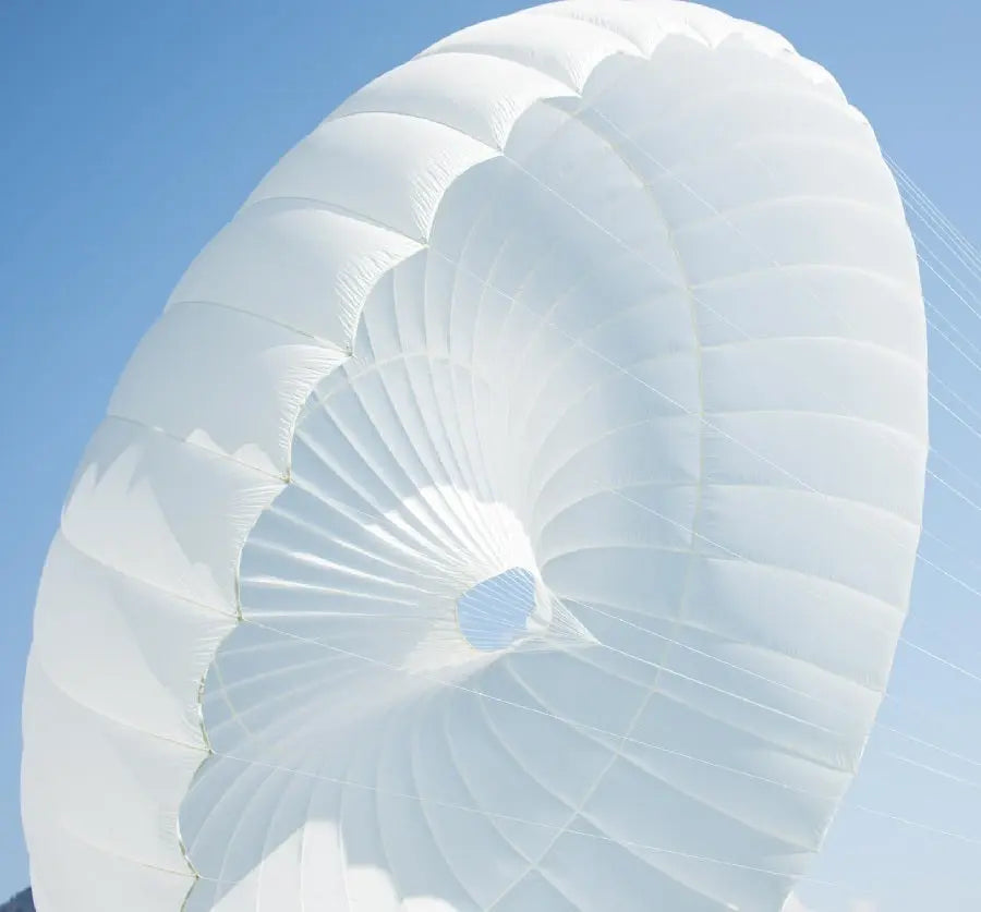 Icaro Albatros Notschirm, weißer Rundkappenschirm im Himmel, ideal für Gleitschirmpiloten, bekannt für schnelle Öffnung und hohe Stabilität.