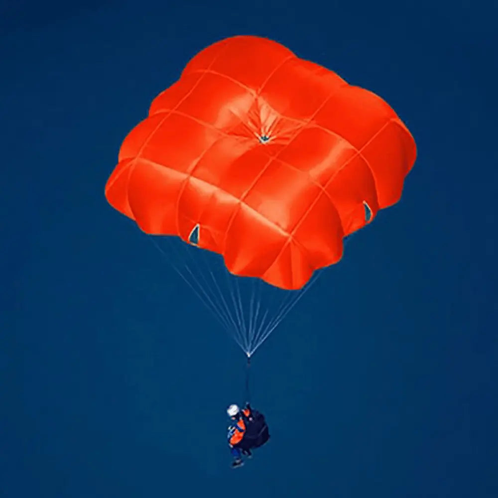 Person unter rotem Niviuk Octagon 2 Rettungsschirm im Flug, bietet Stabilität und Sicherheit für Gleitschirmflieger, passend für hochwertige Schweizer Gleitschirm-Ausrüstung.