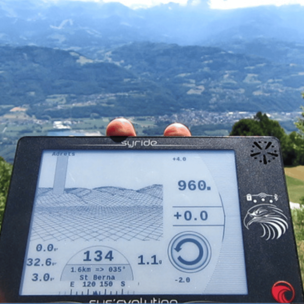 Syride SYS Evolution - Ein GPS-Variometer mit Touchscreen, ideal für Experten im XC-Fliegen, gezeigt in einer Hand vor einer Berglandschaft.