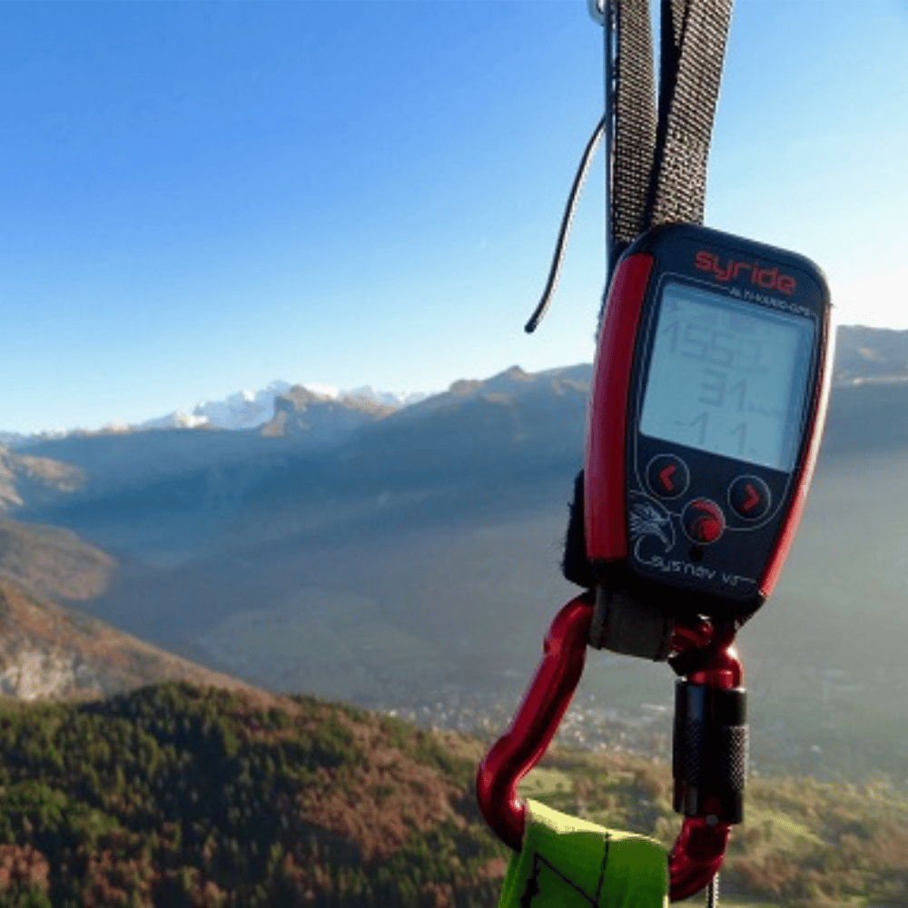 Syride SYS&#39;Nav V3 Gerät an einem Gurt, ideal für Gleitschirmflieger mit GPS, Variometer und G-Sensor, sichtbar auf einem Bergabenteuer.