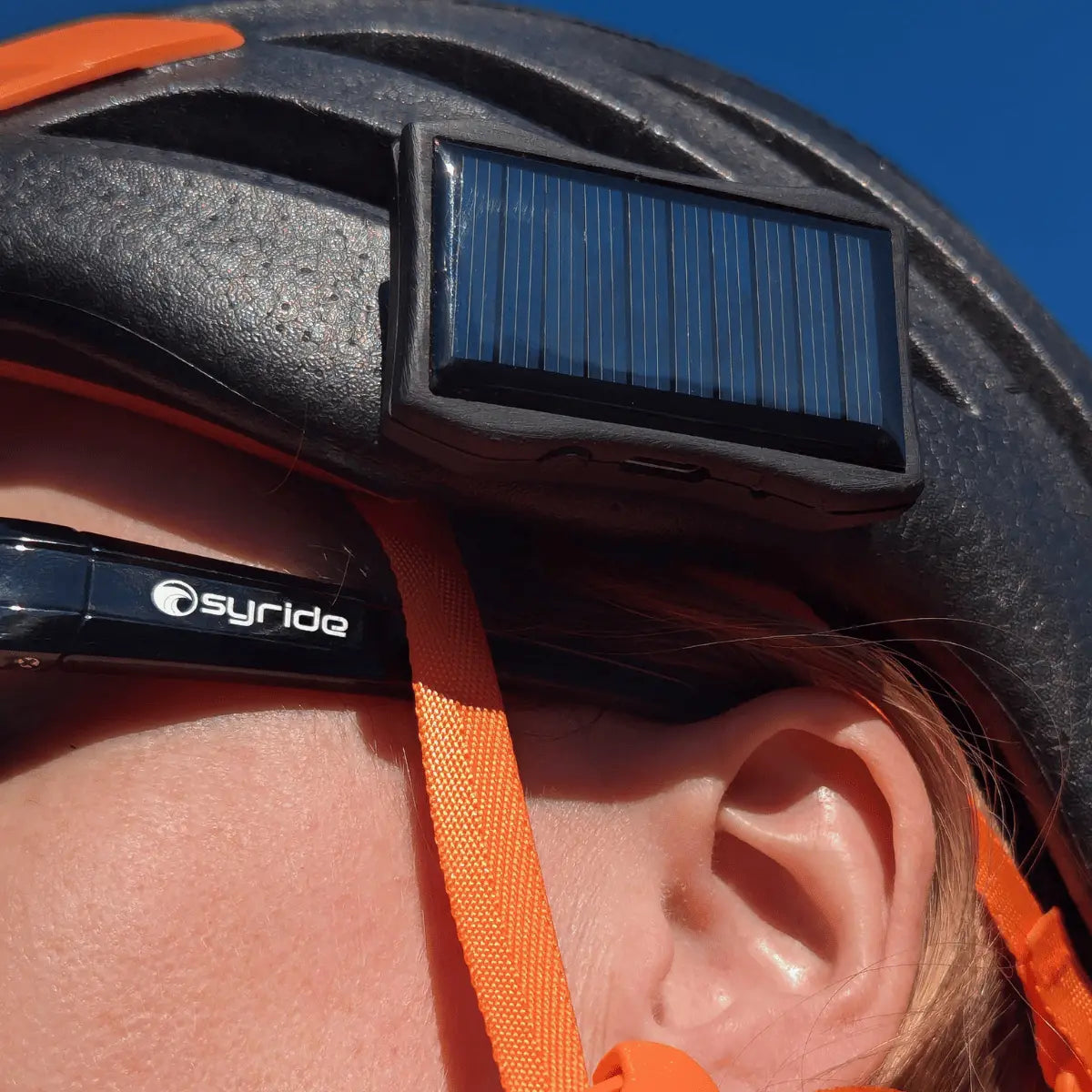 Person trägt einen Helm mit befestigtem Syride Solar Solarzellen-Variometer, geeignet für Paragliding und Fly Electronics bei blauem Himmel.