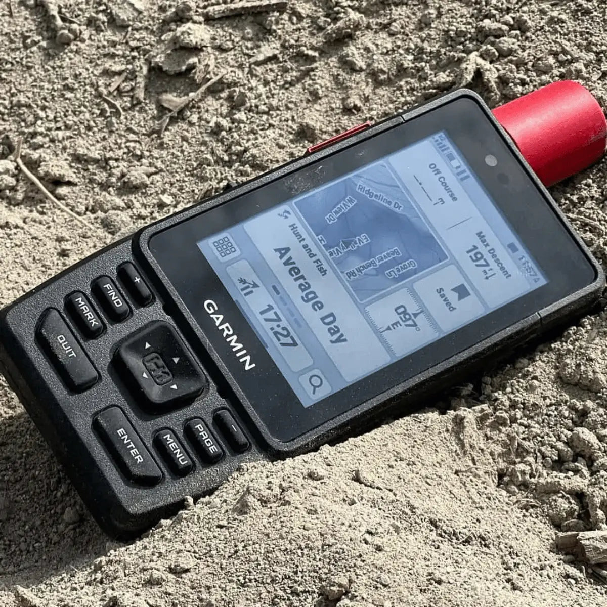 Garmin GPSMAP H1i Plus Handheld-GPS-Gerät im Sand mit detailliertem Bildschirm und roten Antennenkappe.