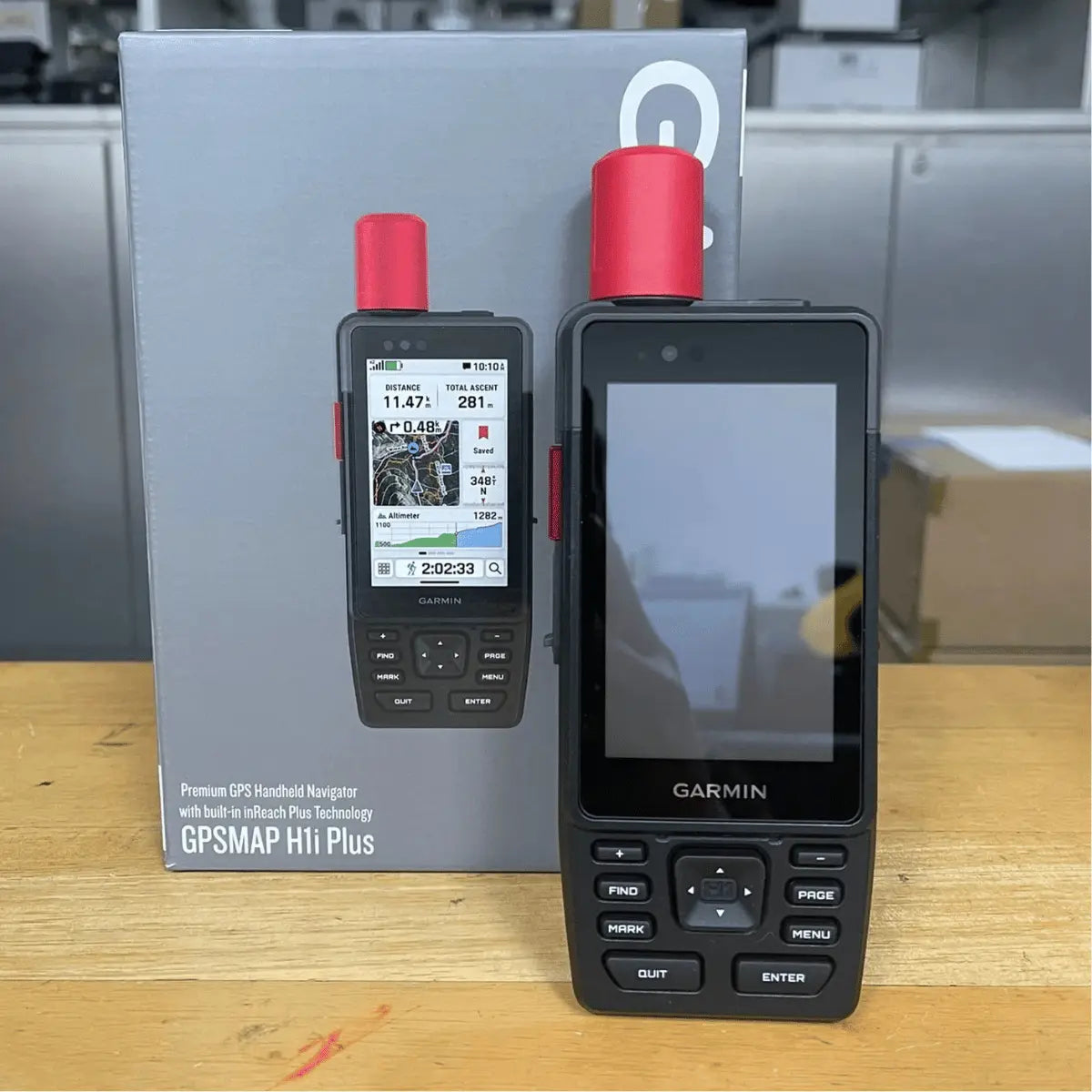 Zwei Garmin GPSMAP H1 & H1i Plus Handheld-Navigationsgeräte mit roter Antenne, eines mit eingeschaltetem Bildschirm, das andere mit Verpackung.