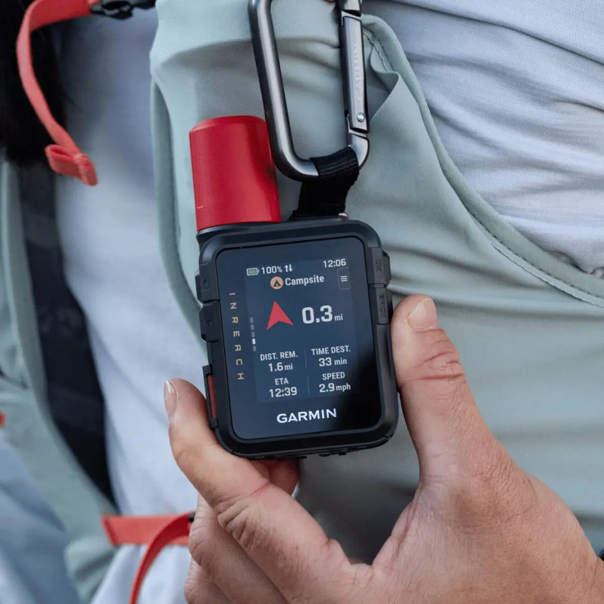 Kompakter Garmin inReach Mini 3 Plus Satellitenkommunikator mit rotem Aufsatz, befestigt an einer Rucksackschlaufe und in der Hand gehalten.