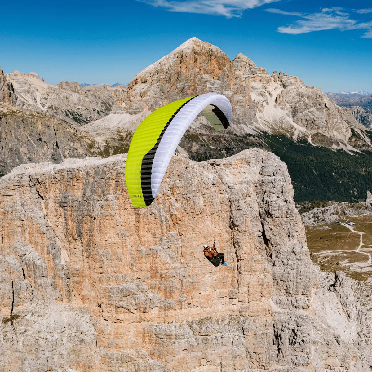 Gin Bandit 2 Ultra Light Gleitschirm, lime-grünes Segel, fliegt neben steiler Felswand, ideal für Thermik, XC und Hike & Fly, bietet Leistung und Leichtigkeit.