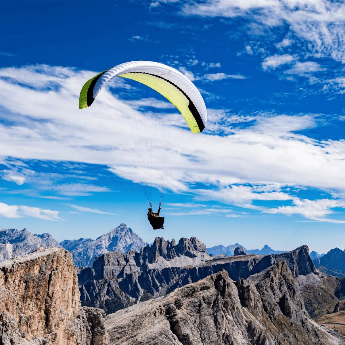 Paraglider mit Gin Bandit 2 Ultra Light schwebt über felsiger Berglandschaft, ideal für Thermik und XC-Flüge, verbindet hohe Leistung mit ultraleichtem Design.