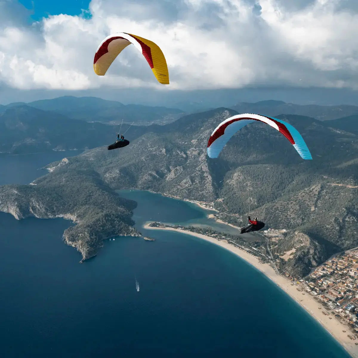 Zwei Gleitschirmpiloten fliegen über eine Küstenlandschaft mit dem Gin Bonanza 3 (EN-C), einem leistungsstarken Gleitschirm für erfahrene Piloten.