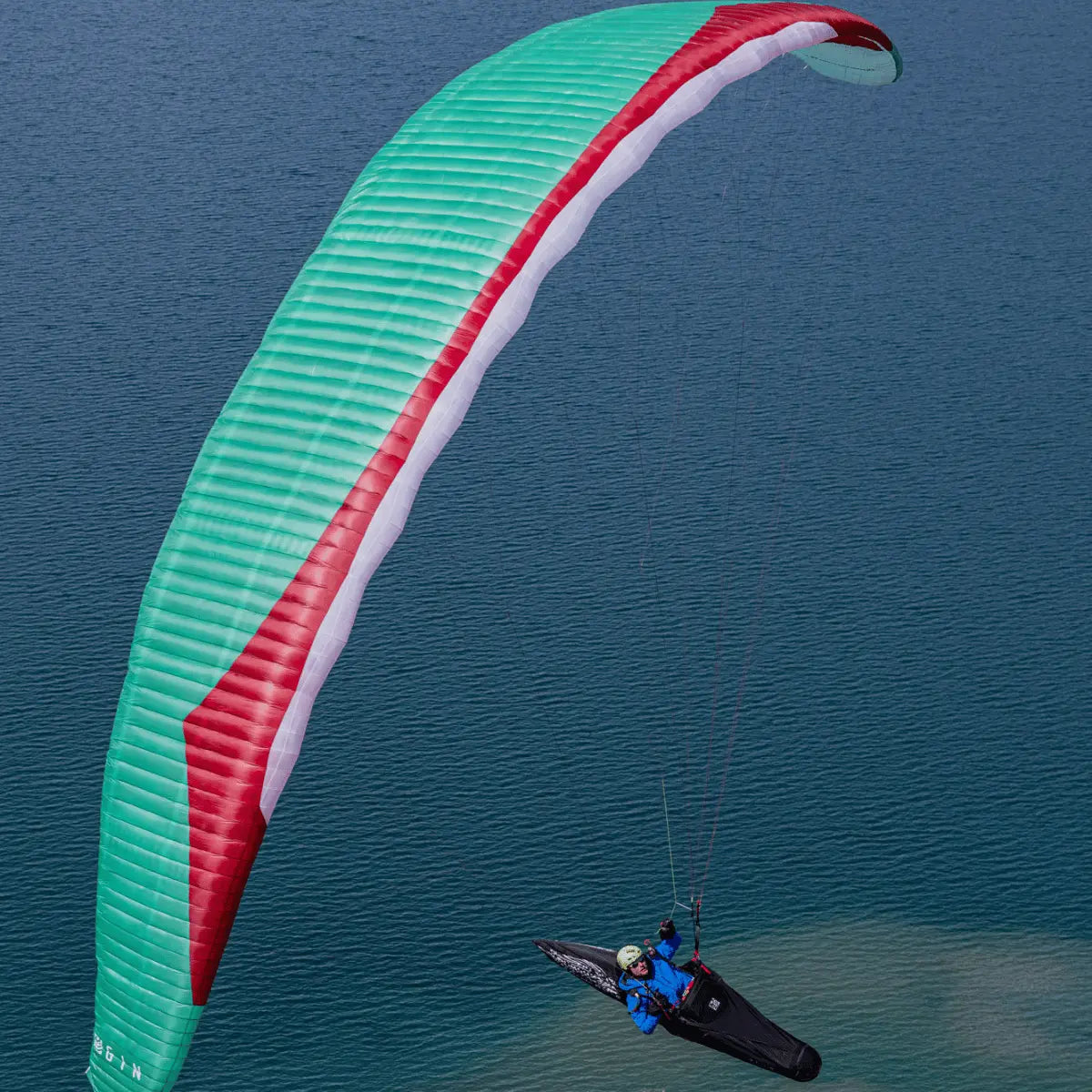 Person paraglidet mit einem Gin Boomerang 12 EN-CCC über Wasser, einem High-Competition Gleitschirm für erfahrene Piloten.