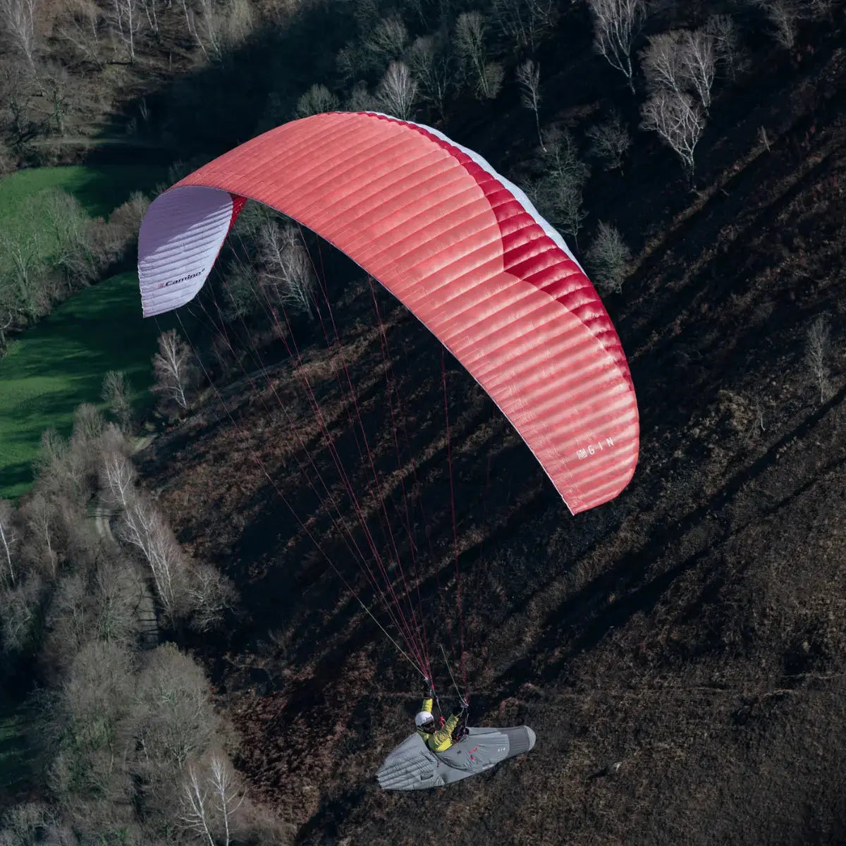 Paraglider Gin Camino 2 Light (EN-C) in der Luft, Pilot schwebt über einem Hügel, ideal für XC und Hike & Fly, hohe Leistung bei geringem Gewicht.