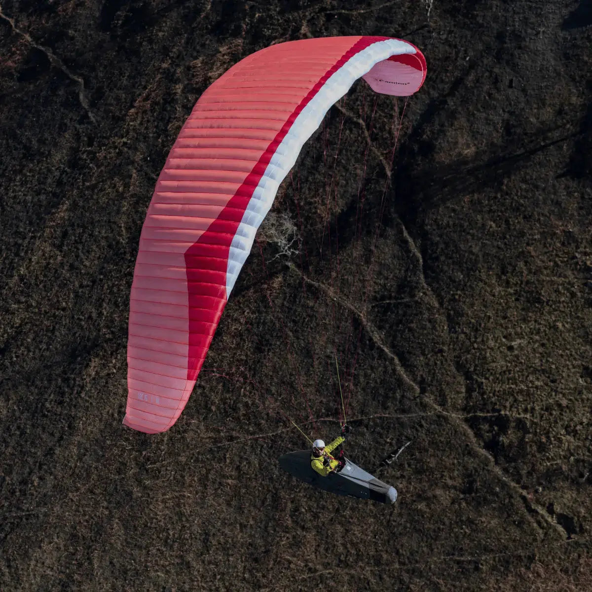 Pilot fliegt mit Gin Camino 2 Light (EN-C) Gleitschirm über bergiges Gelände, ideal für erfahrene XC-Piloten, die Leistung und leichtes Gewicht suchen.