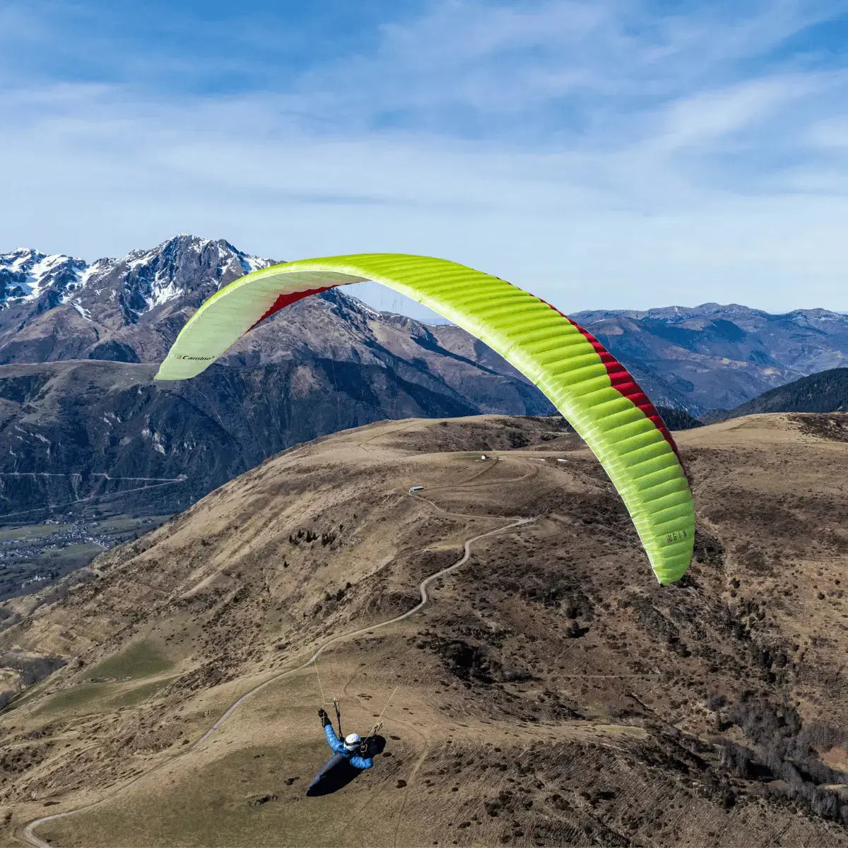 Pilot fliegt Gin Camino 2 Light (EN-C) Gleitschirm über hügelige Landschaft, ideal für XC und Hike & Fly, bekannt für Leistung und Leichtbau.