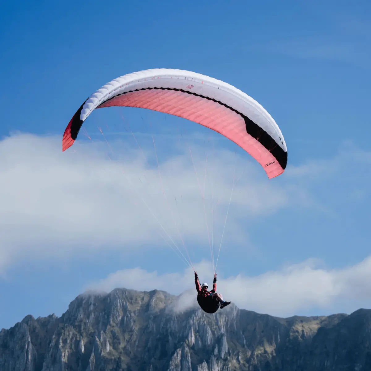 Person beim Paragliden mit Gin Elise Light Weight EN-A Gleitschirm, ideal für Einsteiger und Hike & Fly, vor bewölktem Himmel und Berglandschaft.