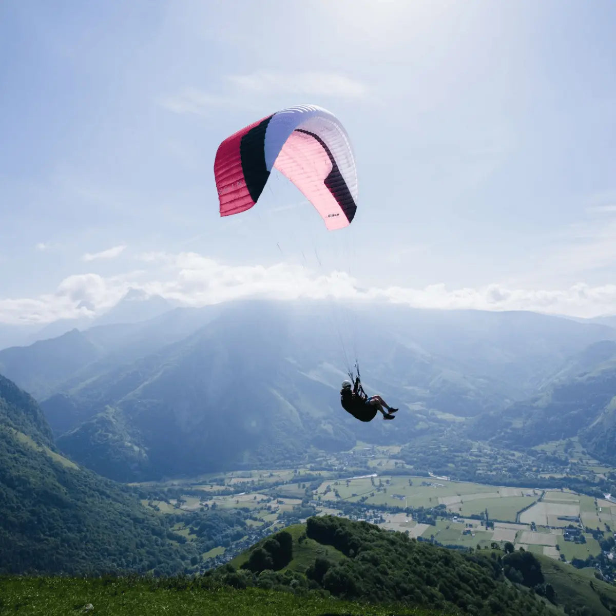 Gin Elise Light Weight EN-A Gleitschirm beim Flug über bewaldetes Bergtal, ideal für Schulung und Hike & Fly, zeigt hohe Sicherheit und leichtes Handling.