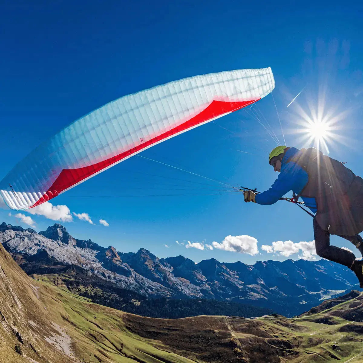 Person hält den GIN Explorer 2 Gleitschirm über einem Berg, ideal für abenteuerliches Paragliding. Hochwertiger Leichtschirm mit exzellenter Leistung und Stabilität.
