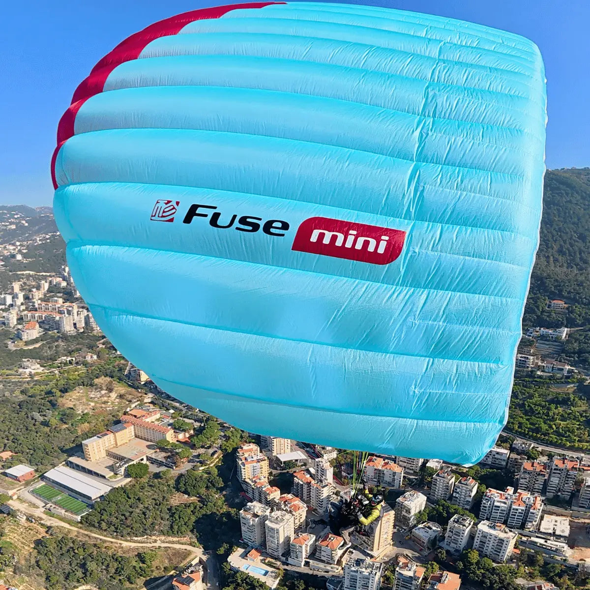 Gin Fuse mini (EN-B) - Strong Wind Tandem in Flug, über einer sonnigen Stadt, ideal für erfahrene Tandempiloten bei anspruchsvollen Windbedingungen.