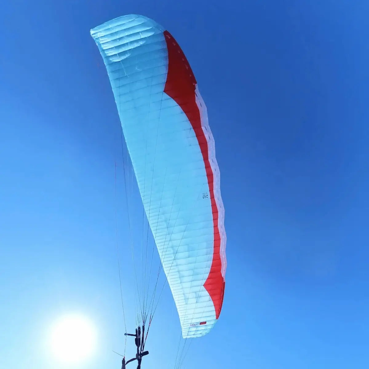 Gin Fuse mini (EN-B) - Strong Wind Tandem von unten gegen blauen Himmel, mit sichtbaren Traglinien und Teil des Piloten-Riser-Systems.