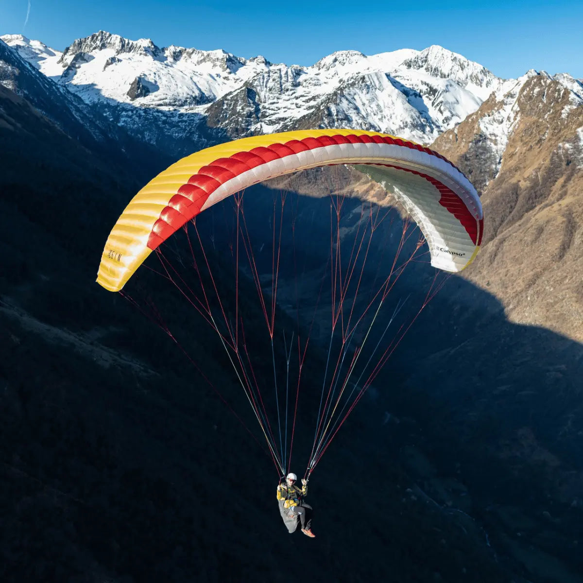 Person gleitet mit Gin Calypso 2 Light Gleitschirm über Bergtal. Der Schirm bietet hohe Sicherheit, präzises Handling und eignet sich ideal für Thermikflüge.