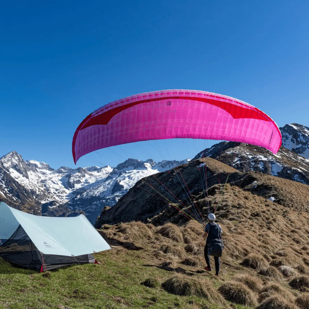 Gin Calypso 2 Light Gleitschirm bereit zum Start, neben leichtem Zelt auf alpinem Hang, ideal für Thermik- und Hike & Fly-Abenteuer.