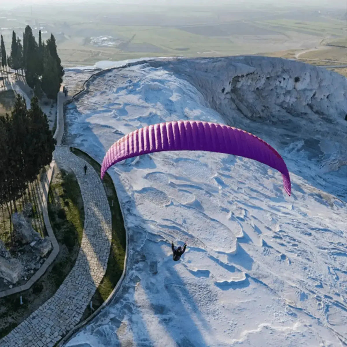 Gin Evora (Mid EN-B) Gleitschirm über weißen Travertinterrassen; ideal für Thermik und Streckenflug, bietet präzises Handling und hohe Gleitleistung für ambitionierte Piloten.