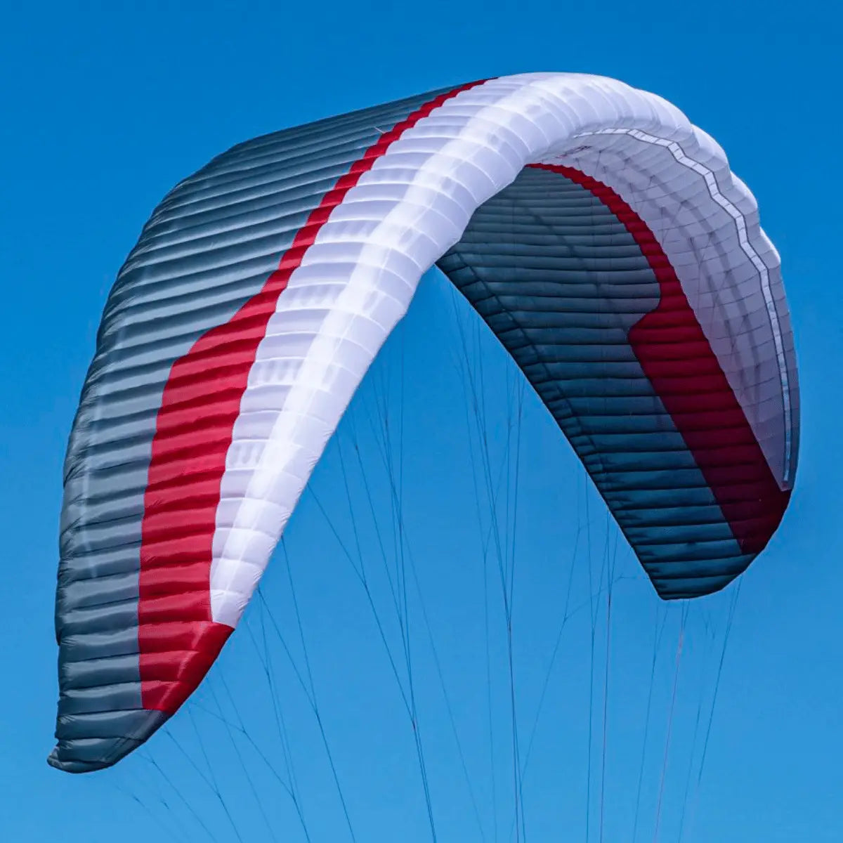 Gin GTO 3 EN-C Gleitschirm mit rot-grauen Zellen, schwebend am blauen Himmel, ideal für erfahrene XC-Piloten, bietet kompromisslose Leistung und Stabilität.