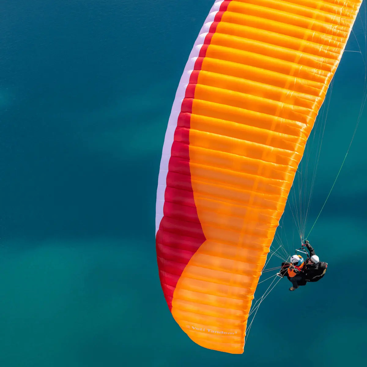 Gin Yeti Tandem 3 (EN-A) Gleitschirm, zwei Personen fliegen über blau-grünem Wasser, ideal für Hike & Fly Abenteurer, ultraleicht und sicher für Tandemflüge.