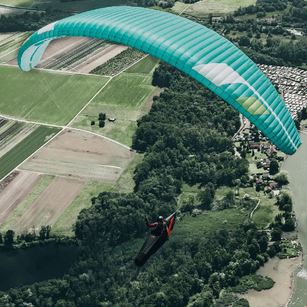 Niviuk Artik 7 P (EN-C) Gleitschirm mit grünem Schirm, schwarzem und rotem Anzug, ideal für XC und Hike & Fly Abenteuer.