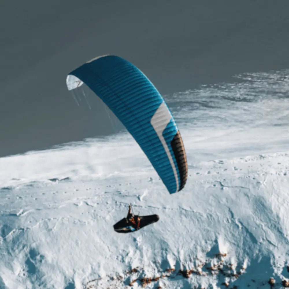 Niviuk Artik R 2 (EN-C) Gleitschirm in der Luft mit Bergen im Hintergrund, ideal für Streckenfliegen und Wettkampf, bietet hohe Leistung und Stabilität. Perfekt für fortgeschrittene Piloten.