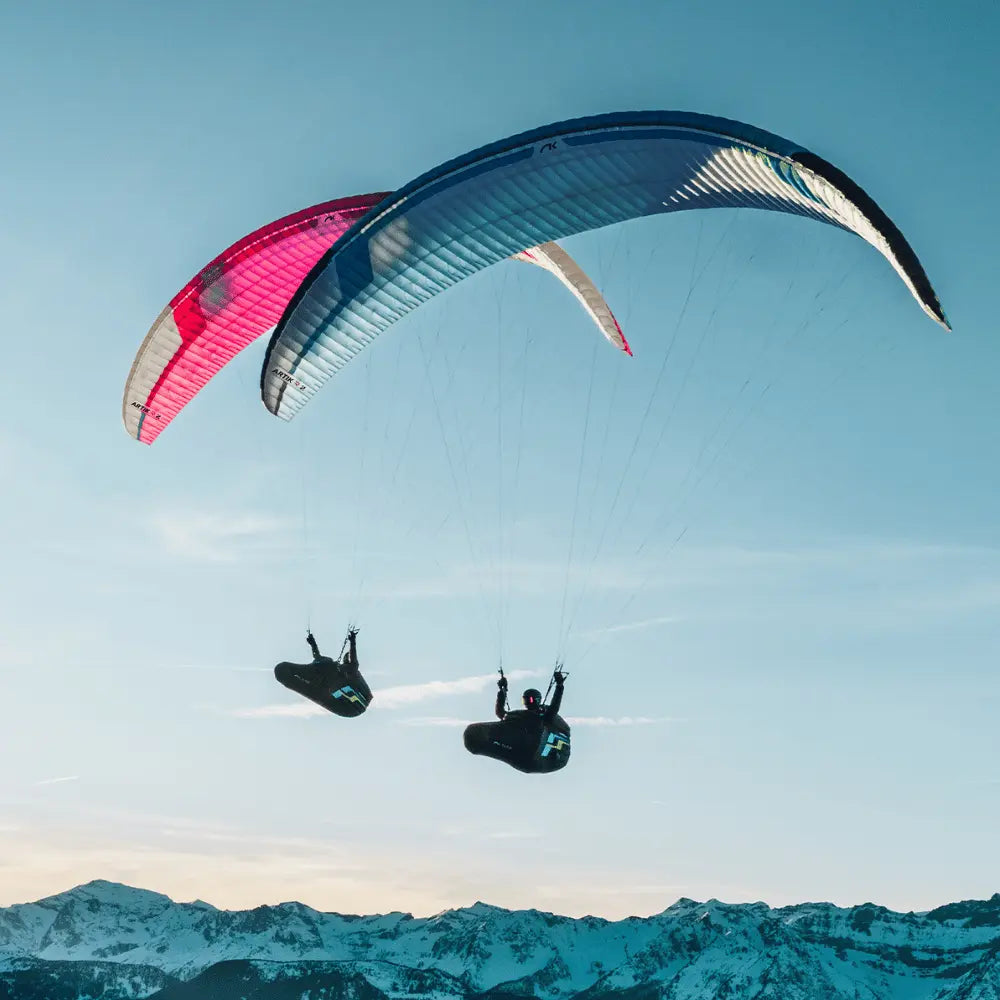 Niviuk Artik R 2 (EN-C) im Einsatz: Person mit Fallschirm in der Luft, ideal für Streckenfliegen und Wettkämpfe, bietet Geschwindigkeit, Stabilität und hohe Leistung.