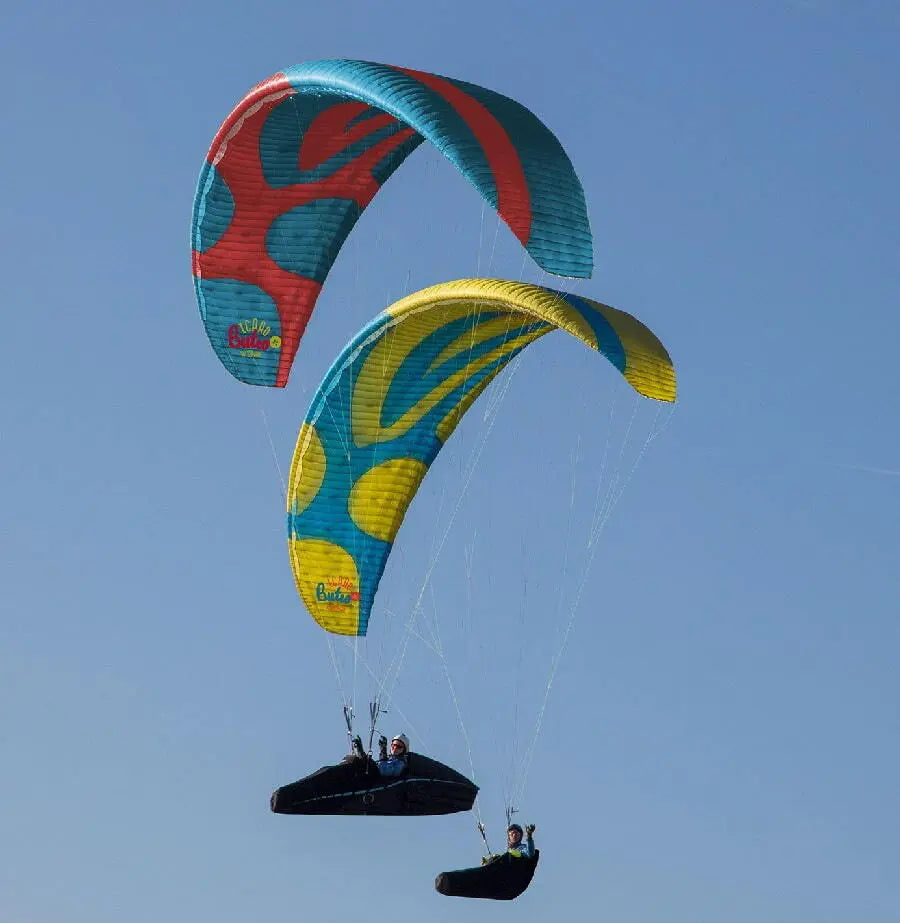Icaro Buteo XC Gleitschirm im Einsatz, zeigt Menschen beim Paragliding im Himmel, ideal für leistungsorientierte Streckenflüge mit hoher Sicherheit und Vielseitigkeit.
