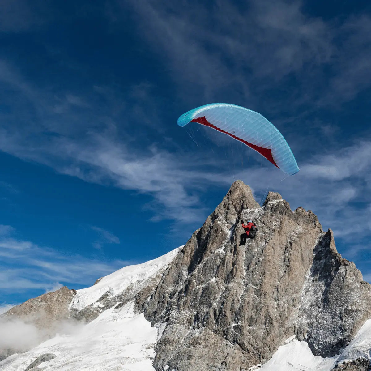Pilot startet mit Gin Yeti 6 Hike & Fly von schneebedecktem Berggrat, blauer Schirm über ihm, ideal für Einsteiger im alpinen Gleitschirmfliegen.