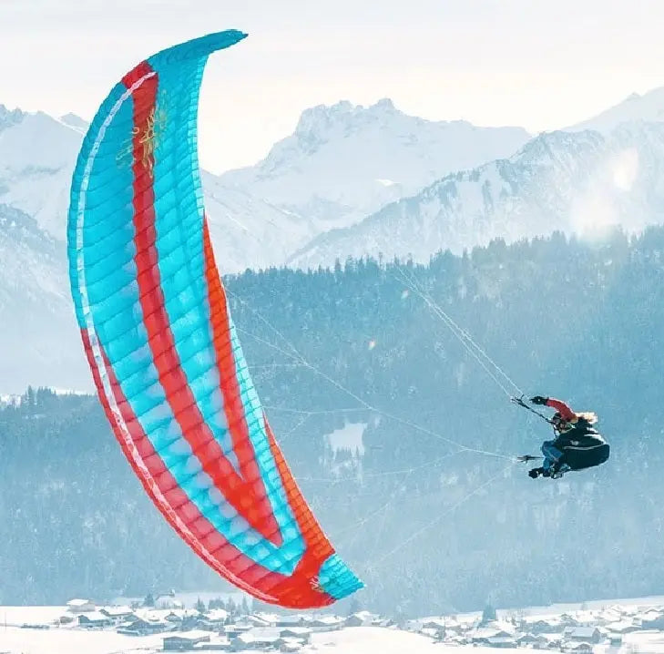 Icaro Gravis 2 Gleitschirm über schneebedecktem Berg, ideal für thermische Flüge und XC-Piloten, bietet herausragende Leistung und Sicherheit in der B-Klasse.