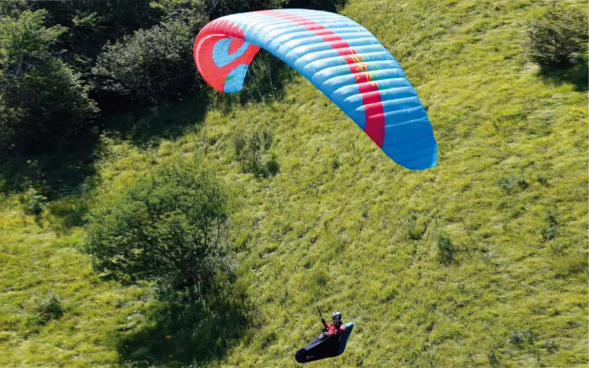 Icaro Gravis 2 (Mid EN-B) beim Paragliding über einem grünen Feld, ideal für sichere und leistungsstarke Flüge. Perfekt für Abenteuer und Freizeit.