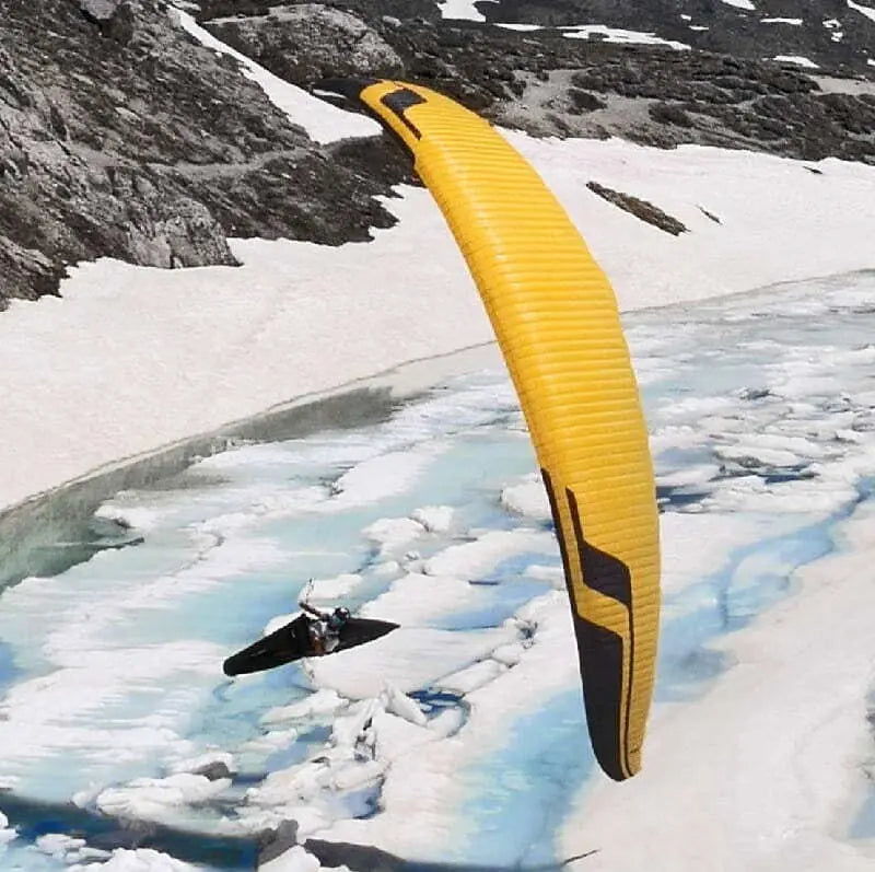 Niviuk Icepeak X-One (EN-CCC) Gleitschirm über verschneitem Berg, symbolisiert Geschwindigkeit und Stabilität, ideal für Wettbewerbsflüge.