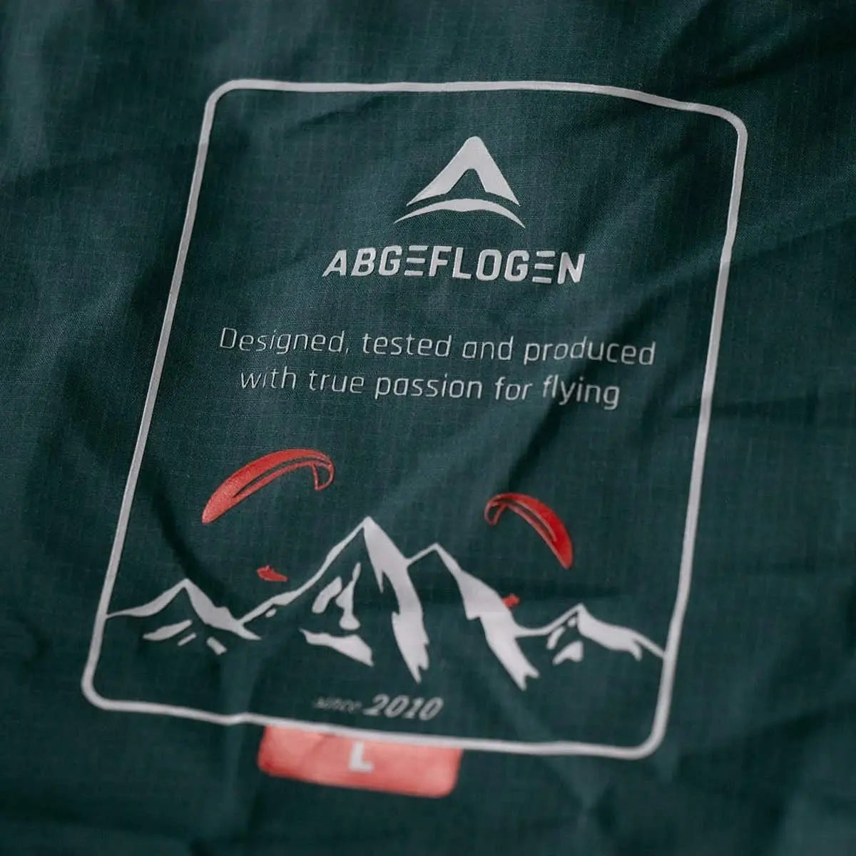 Aventus 3.1 Gleitschirm Jacke mit weißem Logo auf blauer Oberfläche, ideal für alle Jahreszeiten und Flüge, bei Paragliding24.ch erhältlich.