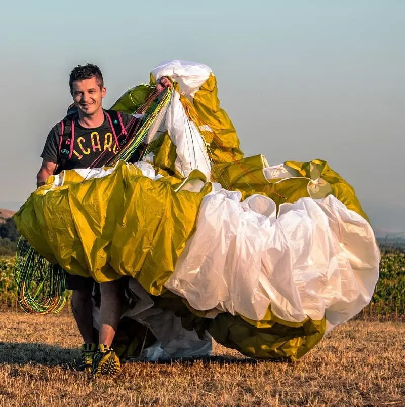 Icaro Pandion 2 Low EN-B: Mann hält gelben Gleitschirm, ideal für sicheren B-Klasse-Einstieg und entspannte Flüge. Perfekt für Thermikliebhaber und Genussflieger.